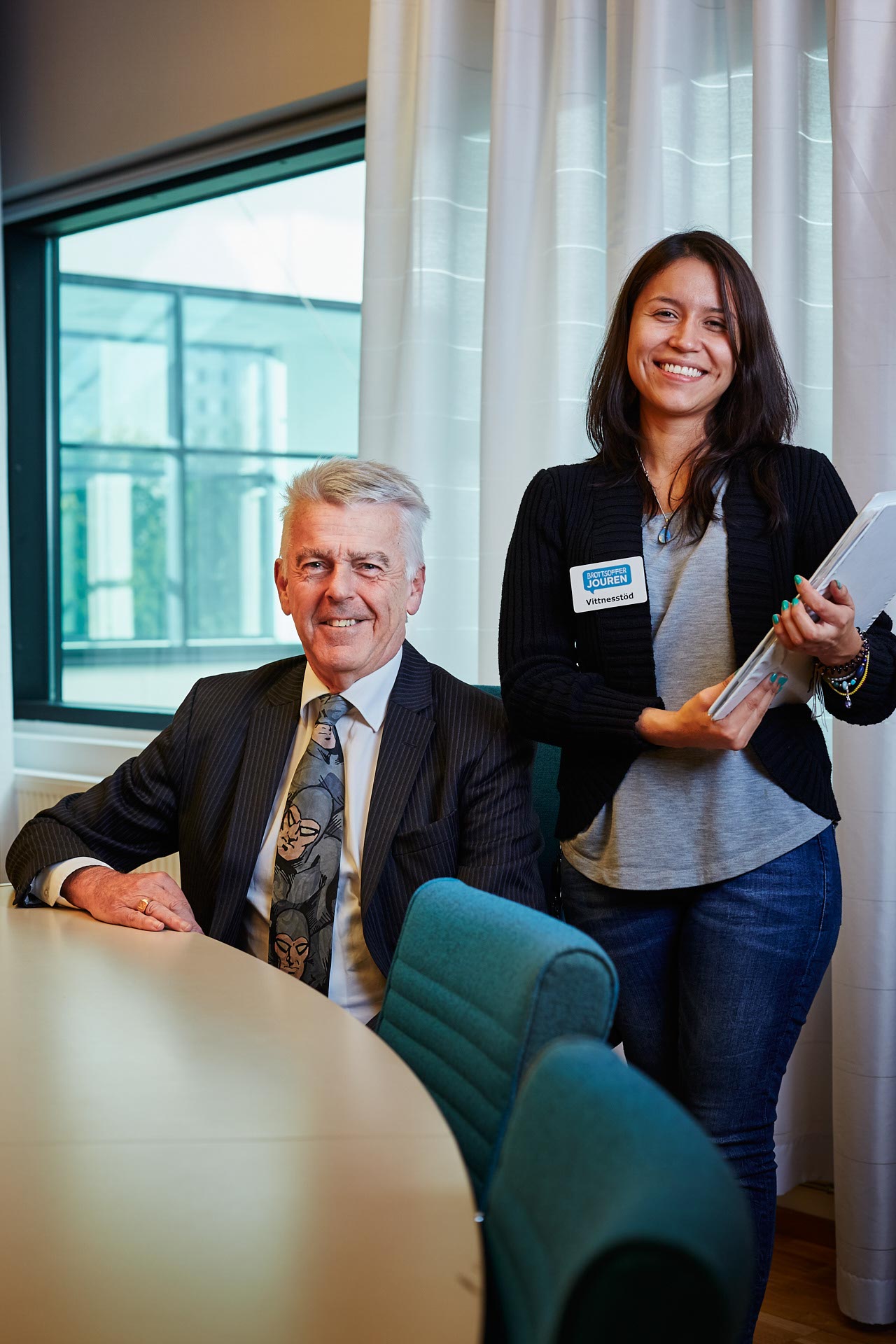 Michael Mittelton och Laura Pena från Brottsofferjouren vid ett mötesbord i Sollentuna tingsrätt, leende mot kameran. Fotograferat för ett kundcase åt en IT-leverantör som tillhandahöll digitala lösningar...